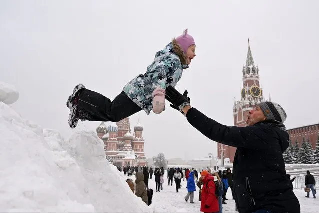 A child jumps from a pile of snow on Moscow's snow-covered Red Square, on December 17, 2023. The height of snowdrifts in Moscow on December 17, 2023 reached 38 centimeters, breaking an 82-year-old record in the entire history of meteorological observations. (Photo by Natalia Kolesnikova/AFP Photo)