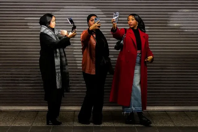 Women take selfies as they wait for the subway at Penn Station, New York, December 26, 2023. (Photo by Charly Triballeau/AFP Photo)