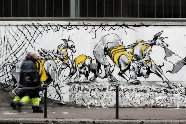 Peole walk past art work on a giant mural by French artist collective Black Lines celebrating the yellow vests movement in Paris, France, February 8, 2019. (Photo by Benoit Tessier/Reuters)