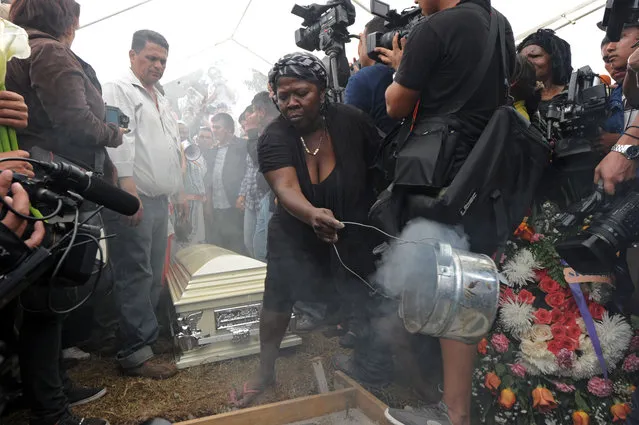 A Garifuna woman makes a ritual during murdered indigenous activist Berta Caceres' funeral in La Esperanza, 200 km northwest of Tegucigalpa, on March 5, 2016. Honduran indigenous activist Berta Caceres, a renowned environmentalist whose family has labeled her killing an assassination, was shot dead on March 3 at her home in La Esperanza. (Photo by Orlando Sierra/AFP Photo)