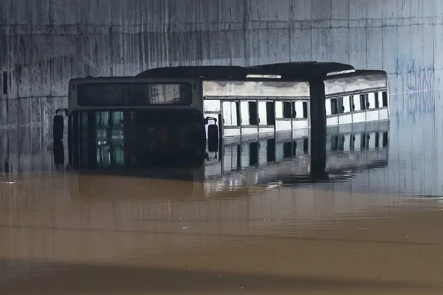 A view of a submerged bus under a bridge after flooding caused by heavy rainfall in Athens, Greece, 15 October 2021, during the second day of the severe “Ballos” weather phenomenon. Primary and secondary schools in the Attica Region will remain closed due to severe weather conditions. (Photo by Orestis Panagiotou/EPA/EFE)