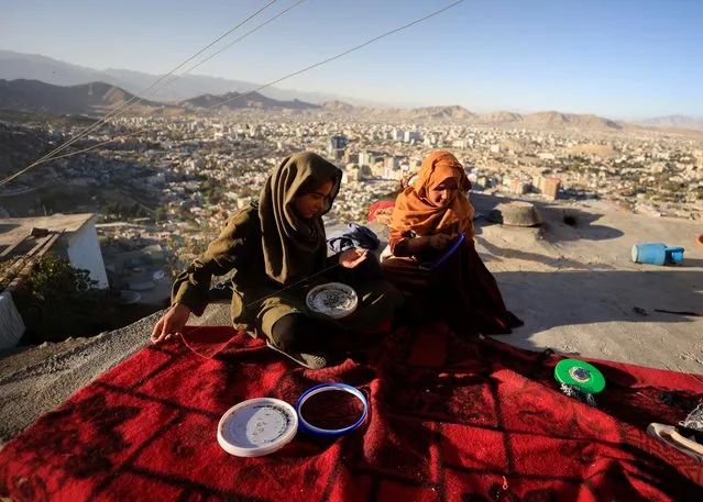 Zarmina,14, and Guldana, 15, work on their embroidery piece as they sit outside their house at Tv mountain in Kabul, Afghanistan on October 15, 2021. (Photo by Zohra Bensemra/Reuters)