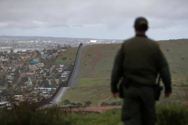 In this February 5, 2019, file photo, Border Patrol agent Vincent Pirro looks on near a border wall that separates the cities of Tijuana, Mexico, and San Diego, in San Diego. U.S. border authorities say they’ve started to increase the biometric data they take from children 13 years of age and younger, including fingerprints, despite privacy concerns and government policy intended to restrict what can be collected from migrant youth. (Photo by Gregory Bull/AP Photo/File)