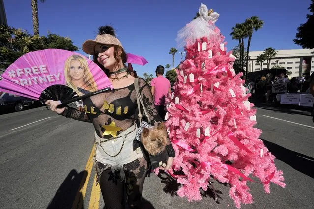 Britney Spears supporter Phoebe Price and her dog Henry take pictures next to a “Free Britney” Christmas tree set by fans outside a hearing concerning the pop singer's conservatorship at the Stanley Mosk Courthouse, Friday, November 12, 2021, in Los Angeles. A Los Angeles judge ended the conservatorship that has controlled Spears' life and money for nearly 14 years. (Photo by Damian Dovarganes/AP Photo)