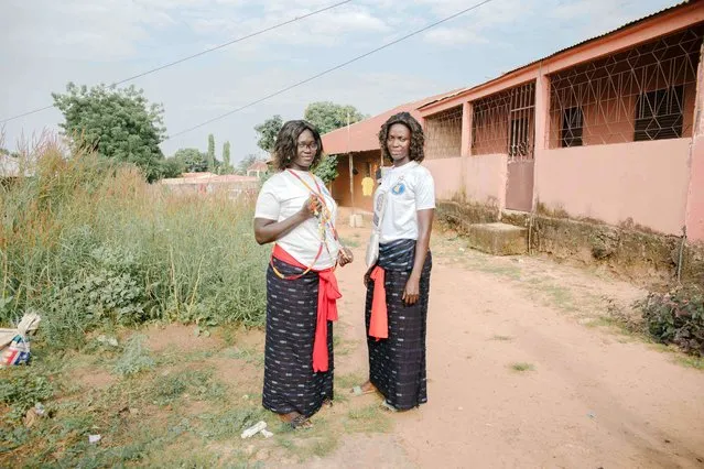 Two women pose for a portrait in front of the house where a Diola circumcision ceremony is held in Bissau on November 14, 2021. The Diola are a West African ethnic group living in Gambia, southern Senegal (Casamance) and Guinea-Bissau. According to tradition and specific rules, men must be circumcised in their native village. (Photo by Carmen Abd Ali/AFP Photo)