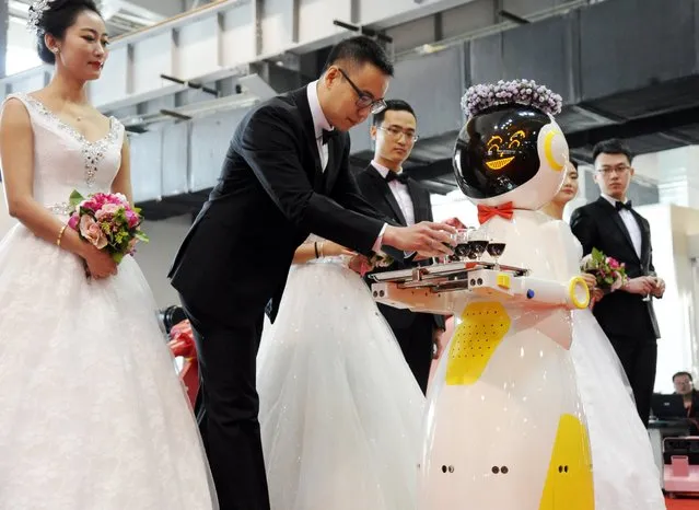 A service robot takes glasses of red wine for brides and grooms during a group wedding ceremony at a robot factory on January 20, 2016 in Shenyang, Liaoning Province of China. Various types of robot served a five-couple group wedding at a robot factory on Wednesday in Shenyang. (Photo by ChinaFotoPress via Getty Images)