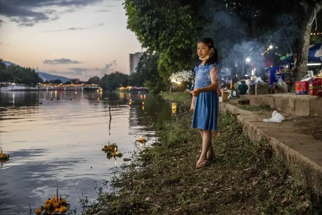 A young Thai girl plays with a sparker from a Krathong along the Ping River during Loy Krathong on November 19, 2021 in Chiang Mai, Thailand. Chiang Mai hosts its annual Loy Krathong Festival, a cultural celebration where Thais release floating lantern rafts onto the Ping River for good luck on the 12th Thai lunar month. Loy Krathong 2021 is the first major festival held in Thailand since reopening to international tourists on November 1, 2021. (Photo by Lauren DeCicca/Getty Images)