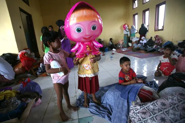 An ethnic Rohingya young girl holds a balloon of Russian cartoon character “Masha” at a temporary shelter in Lapang, Aceh province, Indonesia, Thursday, May 14, 2015. More than 1,600 migrants and refugees from Myanmar and Bangladesh have landed on the shores of Malaysia and Indonesia in the past week and thousands more are believed to have been abandoned at sea. (Photo by Binsar Bakkara/AP Photo)