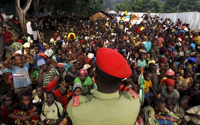 A Tanzanian policeman watches over as Burundian refugees gather on the shores of Lake Tanganyika in Kagunga village in Kigoma region in western Tanzania, to they wait for MV Liemba to transport them to Kigoma township, May 17, 2015. (Photo by Thomas Mukoya/Reuters)