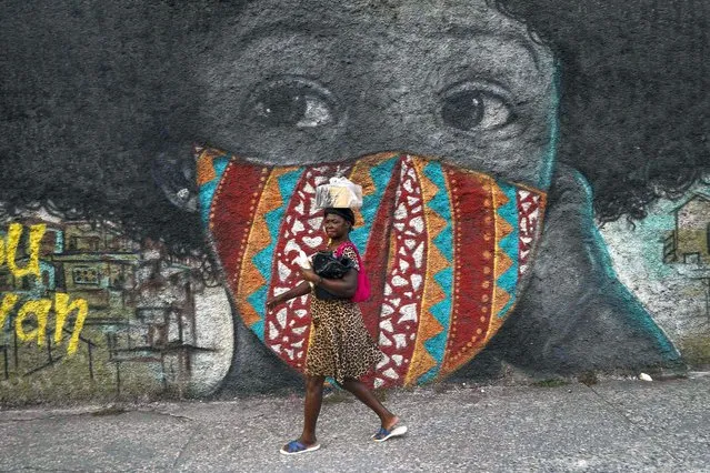 A woman walks past a mural of a woman wearing a protective face mask in in Port-au-Prince, Haiti, Wednesday, October 27, 2021. (Photo by Joseph Odelyn/AP Photo)
