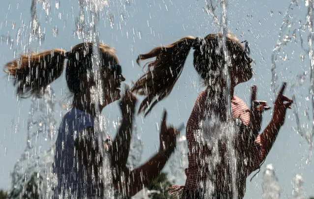 Women react while cooling down in a fountain on a hot summer day in central Moscow, Russia on June 4, 2019. (Photo by Maxim Shemetov/Reuters)