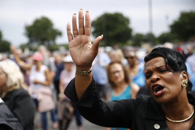 Virginia Beach, Va., council member Sabrina Wooten holds her hand out as she sings during a vigil in response to a shooting at a municipal building in Virginia Beach, Va., Saturday, June 1, 2019. A longtime city employee opened fire at the building Friday before police shot and killed him, authorities said. (Photo by Patrick Semansky/AP Photo)