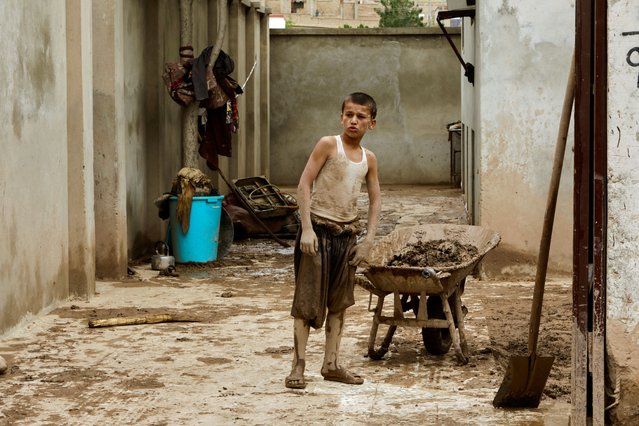 A boy looks on while standing next to a wheelbarrow, in the aftermath of floods following heavy rain, in Sheikh Jalal District, Baghlan province, Afghanistan on May 11, 2024. (Photo by Sayed Hassib/Reuters)