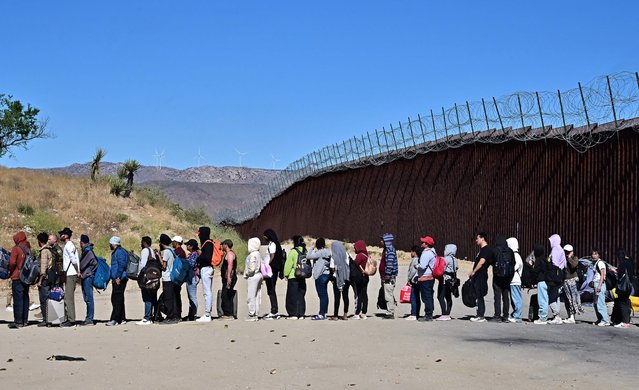 Migrants wait in line hoping for processing from Customs and Border Patrol agents after groups arrived at Jacumba Hot Springs, California, after walking under intense heat from Mexico into the US on June 5, 2024. Migrants from countries such as Turkey, Jordan, Guatemala, Nicaragua, China, India and Colombia made their way on foot into the United States today before being met with by Customs and Border Patrol agents for processing. The United States will temporarily close its Mexico border to asylum seekers starting today, June 5, as President Joe Biden as tries to neutralize his political weakness on migration ahead of November's election battle with Donald Trump. The 81-year-old Democrat signed a long-awaited executive order taking effect at midnight to “gain control” of the southern frontier with Mexico, after record numbers of illegal border crossings sparked concerns among voters. (Photo by Frederic J. Brown/AFP Photo)