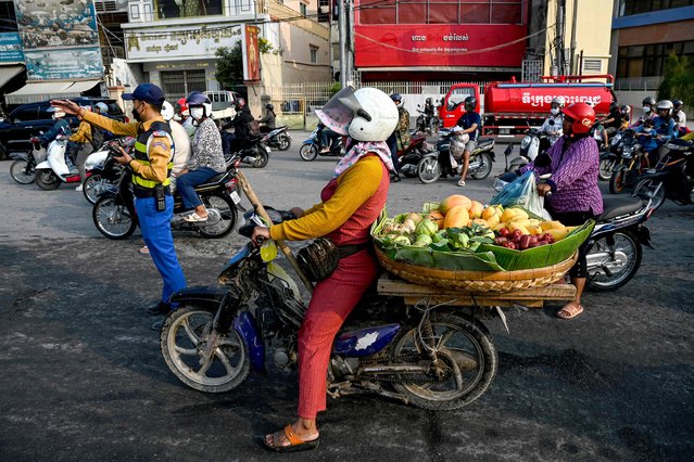 A vendor rides a motorbike loaded with fruits for sale along a street in Phnom Penh on February 6, 2024. (Photo by Tang Chhin Sothy/AFP Photo)