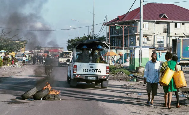 Peacekeepers serving in the United Nations Organization Stabilization Mission in the Democratic Republic of the Congo (MONUSCO) drive past burning tyres as they patrol during mass protests against President Joseph Kabila in the streets of the Democratic Republic of Congo's capital Kinshasa, April 10, 2017. (Photo by Robert Carrubba/Reuters)
