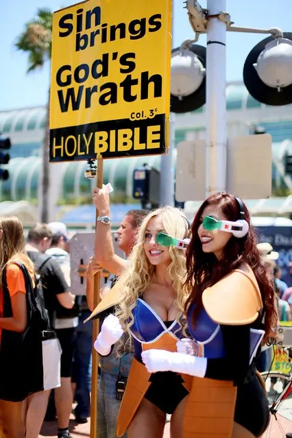 Cosplayers pose for pictures while a picketer holds a pro-religion sign outside of the Convention Center at the 2015 Comic-Con International in San Diego, California July 9, 2015. (Photo by Sandy Huffaker/Reuters)