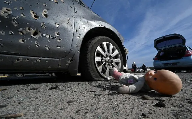 This photograph taken on March 12, 2022 shows an abandoned doll next to a car riddled with bullets in Irpin, north of Kyiv. Russian forces stepped up the pressure on Kyiv on March 12, 2022. The northwest suburbs of the capital, including Irpin and Bucha, have already endured days of heavy bombardment while Russian armoured vehicles are advancing on the northeastern edge. (Photo by Sergei Supinsky/AFP Photo)