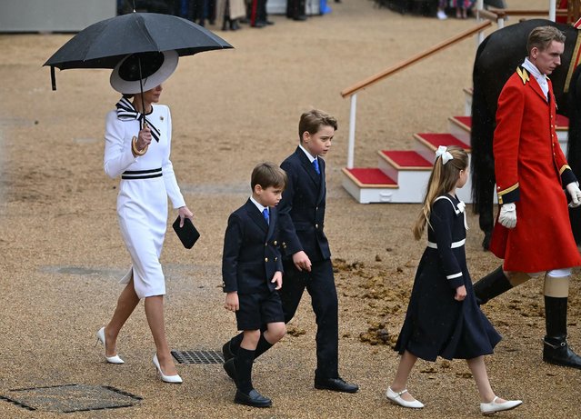 Britain's Catherine, Princess of Wales, shelters from the rain with an umbrella as she walks with her children Britain's Prince George of Wales (C), Britain's Princess Charlotte of Wales (R) and Britain's Prince Louis of Wales back to the Glass State Coach at Horse Guards Parade during the King's Birthday Parade “Trooping the Colour” in London on June 15, 2024. Catherine, Princess of Wales, is making a tentative return to public life for the first time since being diagnosed with cancer, attending the Trooping the Colour military parade in central London. (Photo by Justin Tallis/AFP Photo)