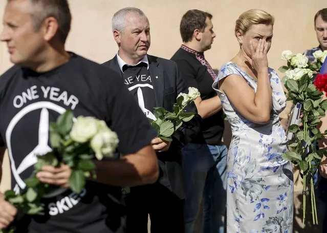 People carry flowers outside the Dutch embassy to commemorate the victims of the downing of Malaysia Airlines MH17 in eastern Ukraine a year ago, in Kiev, Ukraine July 17, 2015. (Photo by Gleb Garanich/Reuters)