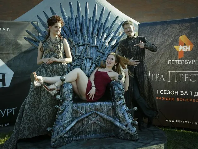 A woman poses for a photo at the throne with actors dressed as persona from a “Game of Thrones”, a fantasy drama television series, during a historical festival in St.Petersburg, Russia, Sunday, July 19, 2015. (Photo by Dmitry Lovetsky/AP Photo)