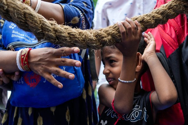 A child holds a rope as he pulls a chariot with others during the return of the chariots festival in Kolkata, India, Monday, July 15, 2024. The return of the chariots marks the end of the nine-day long chariot festival. (Photo by Bikas Das/AP Photo)