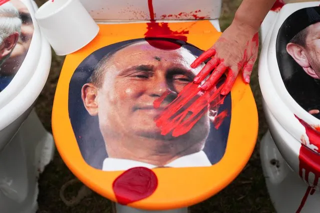 A person puts red paint on a picture of Russian President Vladimir Putin during an anti-Russian demonstration outside the Russian embassy, amid Russia's invasion of Ukraine, in Warsaw, Poland, April 13, 2022. (Photo by Aleksandra Szmigiel/Reuters)