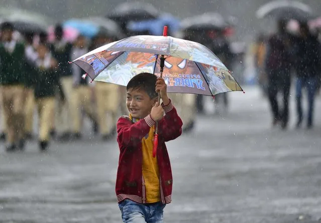 An Indian boy hold an umbrella as he walks to attend the Indian Prime Minister Narendra Modi's first public meeting in Shillong, capital of Meghalaya state, India, 27 May 2016. Modi addressed the North Eastern Council (NEC) meeting with focus on overall development of the region. Modi also inaugurated three major railway projects and laid the foundation stone of the Agartala-Akhaura railway project between India and Bangladesh. (Photo by EPA/Stringer)