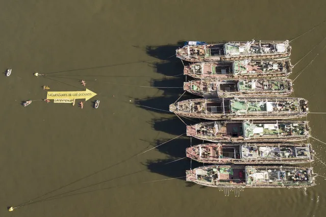 In this aerial handout picture released by Greenpeace, activists of the non-governmental environmental organization display a 25 mts long arrow that reads “Looters of the Oceans” pointing to South Korea's fishing vessels Agnes 103 y Agnes 107 anchored at the port of Montevideo on October 31, 2019, as part of a campaign to denounce destructive fishery activities in the Argentine Sea. - According to Greenpeace, the Argentine Sea is endangered by industrial fishing that destroys the home of the southern right whale (Eubalaena australis) and other iconic species. Fishing vessels border the Argentine Sea taking advantage of the lack of regulation to fish indiscriminately in the South Atlantic, leaving it on the verge of collapse. (Photo by HO/Greenpeace/AFP Photo)