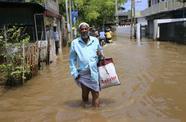 A Sri Lankan man wades through a flooded street in Colombo, Sri Lanka, Sunday, May 28, 2017. Sri Lankan rescuers pulled out more bodies under enormous mudslides on Sunday as the death toll climbed to 146 with 112 others missing. (Photo by Eranga Jayawardena/AP Photo)