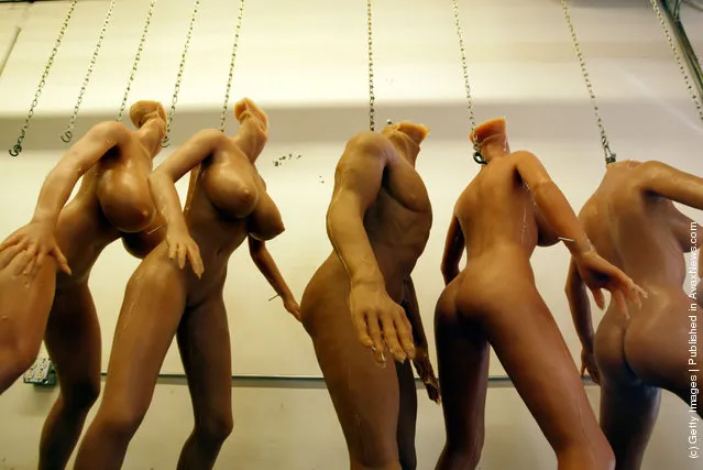 Unfinished silicone RealDoll s*x dolls hang from chains at the Abyss Creations factory