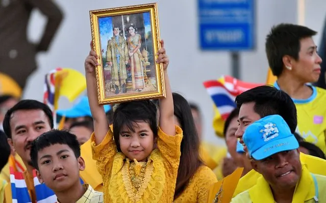 A girl holds up a picture of Thailand's King Maha Vajiralongkorn and Queen Suthida outside the Grand Palace before the Royal Barge Procession in Bangkok, Thailand, December 12, 2019. (Photo by Chalinee Thirasupa/Reuters)