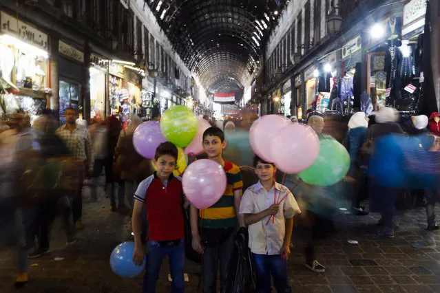 In this May 18, 2017 file photo, Syrian boys pose for a picture as they sell balloons at the Hamadiyah market, in the Old City of Damascus, Syria. Across the capital, new shops are sprouting up, business is brisk, and some people who fled the war years ago are contemplating a return. The Syrian civil war is likely to drag on for years, but in the seat of President Bashar Assad’s government, there is a general feeling that the six-year conflict is winding down. (Photo by Hassan Ammar/AP Photo)