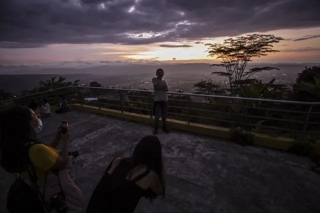 People are seen during the sunset in the Cerro el Santisimo Ecopark in Floridablanca, Santander, Colombia on February 13, 2022. The Cerro del Santisimo Ecopark, is a tourist destination, located in the Vereda Helechales rural part of Floridablanca (Santander), known for having a sculpture of Jesus of Nazareth, including panoramic elevators and a staircase to allow access to the main viewpoint, from where sightseers have a panoramic view of Floridablanca and part of Bucaramanga. Additionally, a sculpted figure at the center of discussions about religious neutrality is placed in the center of the park. (Photo by Juancho Torres/Anadolu Agency via Getty Images)