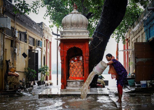 A woman removes rainwater that inundated outside her house on the banks of Yamuna River in the old quarters of Delhi, India on September 4, 2024. (Photo by Ainnie Arif/Reuters)