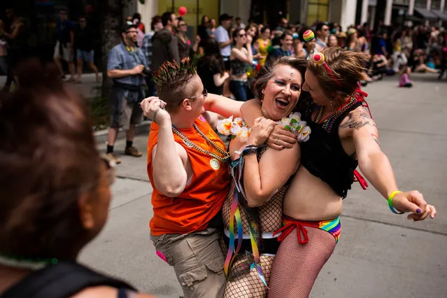 A fish-netted woman leaps from a float to dance with passerby at the 40th annual Seattle Pride Parade Sunday, June 29, 2014, in Seattle, Wash. This year's theme was “Generations of Pride”. (Photo by Jordan Stead/AP Photo/Seattlepi.com)