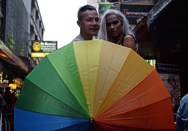 Members of the LGBT community in Thailand gather in front of a bar in Bangkok on June 18, 2016 during a vigil for victims of the worst mass shooting in modern US history in Orlando, Florida. Forty-nine people were killed and 53 wounded when a 29-year-old man ran amok in a packed gay nightclub early on June 12 in Orlando, armed with a legally bought assault rifle. (Photo by Lillian Suwanrumpha/AFP Photo)