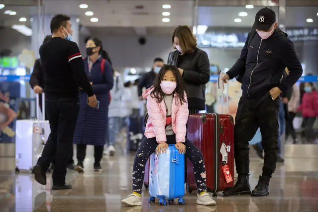 Travelers wear face masks as they stand in the arrivals area at Beijing Capital International Airport in Beijing, Thursday, January 23, 2020. China closed off a city of more than 11 million people Thursday, halting transportation and warning against public gatherings, to try to stop the spread of a deadly new virus that has sickened hundreds and spread to other cities and countries in the Lunar New Year travel rush. (Photo by Mark Schiefelbein/AP Photo)
