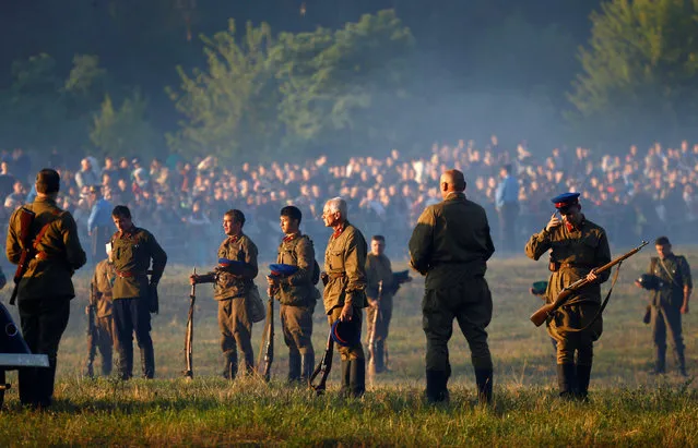 Military enthusiasts dressed as Soviet Red Army stand during the minute of silence after they took part in a re-enactment of a World War II battle at the Hero fortress as they mark the 75th anniversary of the Nazi Germany invasion, in Brest, Belarus June 22, 2016. (Photo by Vasily Fedosenko/Reuters)