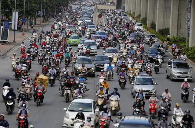 In this June 21, 2017, photo, motorbikes and cars fight for space on a street in Hanoi, Vietnam. Vietnam’s motorbike taxis are seeing their business dry up as customers increasingly opt for ride hailing services like Uber and Grab-Taxi. (Photo by Tran Van Minh/AP Photo)