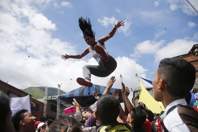 In this Tuesday, July 25, 2017 photo, a woman is thrown into the air during a pro-government candidates' rally in Caracas, Venezuela. President Nicolas Maduro is promoting a constitution rewrite as a means of resolving Venezuela's political standoff and economic crisis, but opposition leaders are boycotting the July 30th vote. The assembly could dramatically reshape government and help Maduro further consolidate his power. (Photo by Ariana Cubillos/AP Photo)