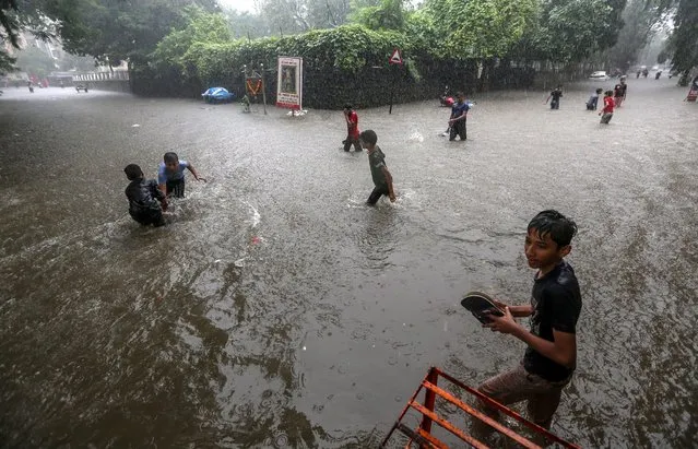 Children wade through a flooded street during heavy rain in Mumbai, India, 05 July 2022. Vehicular movements were affected and local trains were delayed due to heavy rain in the city. (Photo by Divyakant Solanki/EPA/EFE)