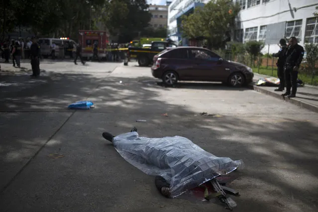 The body of a prison guard lies covered by a plastic sheet outside the Roosevelt Hospital after a shooting, in Guatemala City, Wednesday, August 16, 2017. At least two people were killed and five arrested early Wednesday when alleged gang members shot up one of the country's largest hospitals to free a prisoner, officials said. (Photo by Luis Soto/AP Photo)