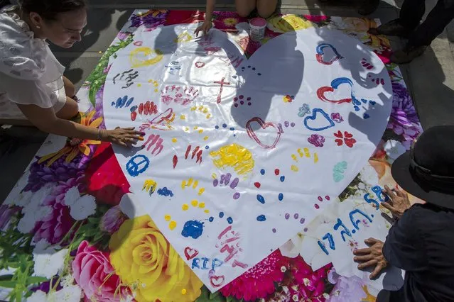 People leave messages on a banner for victims killed in Monday's bomb blast during a religious ceremony near at the Erawan shrine, the site of Monday's deadly blast, in central Bangkok, Thailand, August 21, 2015. (Photo by Athit Perawongmetha/Reuters)