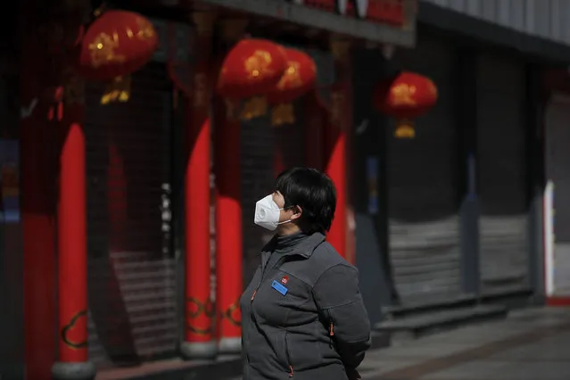 A woman wearing a protective face mask looks at the shuttered business shops at the Wangfujing shopping district following the coronavirus outbreak in Beijing, Tuesday, March 10, 2020. For most people, the new coronavirus causes only mild or moderate symptoms, such as fever and cough. For some, especially older adults and people with existing health problems, it can cause more severe illness, including pneumonia. (Photo by Andy Wong/AP Photo)