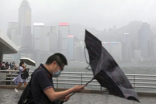 People hold umbrellas in the rain at a waterfront, amid a typhoon warning on the 25th anniversary of the former British colony's handover to Chinese rule, in Hong Kong, China on July 1, 2022. (Photo by Paul Yeung/Reuters)