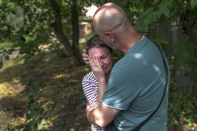 Marina Havrysh, left, is comforted by her husband, Vadim, as she weeps while watching her elderly parents helped into a van to be evacuated to a safer part of the country in the west from their home in Kramatorsk, Donetsk region, eastern Ukraine, Tuesday, August 2, 2022. “I understand that this will be the last time I ever see them”, she said. “You see their age, I can't give them the proper care”. (Photo by David Goldman/AP Photo)