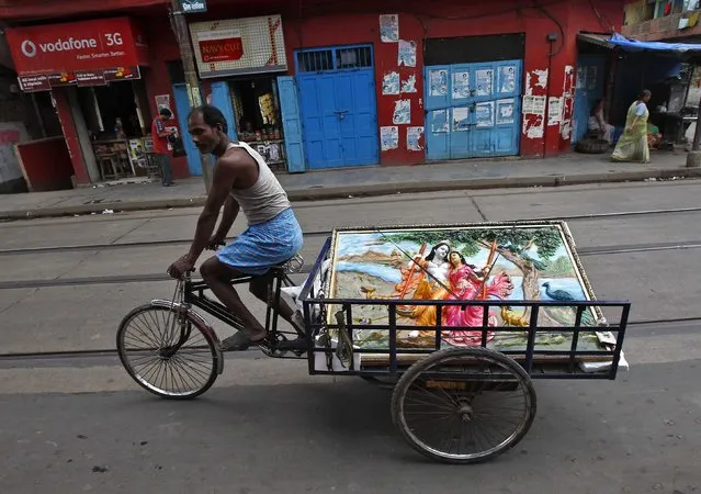 A tricycle rider transports a mural of Hindu Lord Krishna and his consort Radha ahead of the Janmashtami festival in Kolkata August 13, 2014. The festival, which marks the birth anniversary of Lord Krishna, will be celebrated across India on August 18. (Photo by Rupak De Chowdhuri/Reuters)
