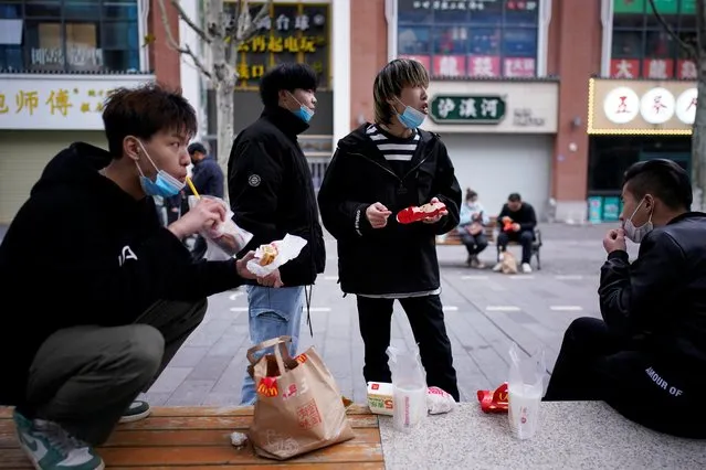 People with face masks eat outside a McDonald's restaurant in Wuhan, Hubei province, China, March 30, 2020. Wuhan, where the coronavirus outbreak first emerged, began lifting a two-month lockdown on Saturday by restarting some metro services and reopening borders, allowing some semblance of normality to return and families to reunite. (Photo by Aly Song/Reuters)