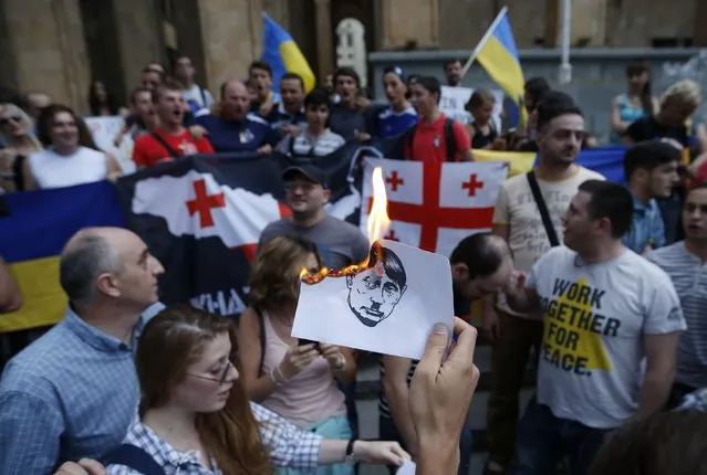 Protesters burn portraits of Russian President Vladimir Putin during a rally in support of Ukraine in Tbilisi August 29, 2014. (Photo by David Mdzinarishvili/Reuters)